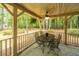 Cozy covered back porch features a ceiling fan, outdoor dining set, and views of the surrounding wooded landscape at 110 Cantering Hills Ln, Summerville, SC 29483