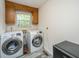 A laundry room equipped with modern washer, dryer, and wood cabinets at 110 Cantering Hills Ln, Summerville, SC 29483