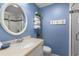 Bright bathroom with blue walls, a round mirror, a sink, and a glass-enclosed shower, creating a fresh and clean space at 1376 Pelican Watch Villas, Seabrook Island, SC 29455