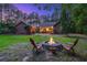 Evening scene of backyard with fire pit, chairs and home lit with warm, inviting lights at 152 Candace Dr, Ridgeville, SC 29472