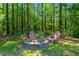 Outdoor fire pit surrounded by lush greenery and trees, with two chairs for relaxing evenings at 152 Candace Dr, Ridgeville, SC 29472