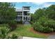 Well-maintained three-story home with manicured lawn, lush greenery, and multiple balconies for outdoor enjoyment at 2213 Rolling Dune Rd, Seabrook Island, SC 29455