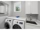 Modern laundry room with white cabinets, sink, front load washer and dryer, and granite countertop at 2213 Rolling Dune Rd, Seabrook Island, SC 29455