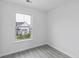 Empty bedroom featuring gray laminate flooring and a window overlooking a neighboring home at 242 Swallowtail Ln, Goose Creek, SC 29445