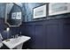 Powder room features stylish palm wallpaper, dark wainscoting, unique art, and pedestal sink at 2648 Balena Dr, Mount Pleasant, SC 29466