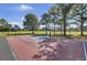 Outdoor basketball court with red surface and blue key surrounded by a black fence and mature trees at 4227 Sawgrass Dr, North Charleston, SC 29420