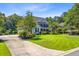 Charming home with a circular driveway, lush landscaping, and mature trees at 4227 Sawgrass Dr, North Charleston, SC 29420