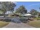 An exterior view of community center with large trees, lush landscape and a white tent for outdoor seating at 4227 Sawgrass Dr, North Charleston, SC 29420