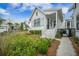 Quaint white cottage home with a welcoming front porch, lush landscaping, and charming architectural details at 7935 Flagship Ln, Johns Island, SC 29455
