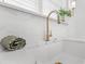 A close-up of a white ceramic sink with gold faucet with white subway tile backsplash, and matching countertop at 80 Smith St, Charleston, SC 29401