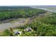 Expansive aerial perspective reveals two houses near a tranquil lake, surrounded by lush greenery and marshland at 8970 Palmetto Rd, Edisto Island, SC 29438