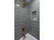 Close-up of a shower with textured, dark grey tiling, gold fixtures, and a built-in niche at 1010 Fiall St, Charleston, SC 29407