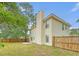 View of the backyard featuring a wood fence, green lawn, and tall trees shading the home at 1042 Cobblestone Blvd, Summerville, SC 29486