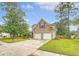 View of the home's two-car garage, driveway, and landscaped front yard lined with mature trees at 1042 Cobblestone Blvd, Summerville, SC 29486