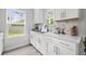 Well-lit kitchen with white cabinets, quartz countertops, stylish backsplash, and exterior view at 1387 Thin Pine Dr, Johns Island, SC 29455