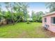 Lush backyard featuring green grass, mature trees, and a charming pink house at 1514 Patterson Ave, Charleston, SC 29412