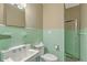 Bathroom with light green tile walls, toilet, sink, mirror, and shower with sliding glass door at 17 Johnson Rd, Charleston, SC 29407