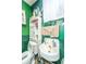 Outdated bathroom featuring vintage sink, toilet, and storage cabinet with green walls and swan decorations at 200 Fishburne St, Charleston, SC 29403