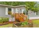 Close-up of a single-story home with gray siding, white trim, wood porch and stairs surrounded by lush landscaping at 201 Frank St, Summerville, SC 29483