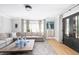 Spacious living room with hardwood floors, neutral sectional sofa, area rug, and black french doors at 202 Bank St, Mount Pleasant, SC 29464