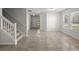 Open-concept living room featuring neutral tile flooring, staircase, bright light, and an entryway door with large windows at 215 Jackson St, Goose Creek, SC 29445