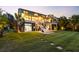 Well-manicured backyard with lush green grass, landscaped patio, and an illuminated exterior of the home at 2363 Palmer Creek Bnd, Charleston, SC 29412