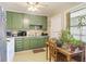 Cozy kitchen featuring vintage green cabinetry, white appliances, and a small dining area with natural light at 2703 Phyllis St, North Charleston, SC 29405