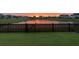 Fenced backyard overlooking a serene pond and other homes in the neighborhood at sunset at 302 Lucca Dr, Summerville, SC 29486