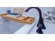Close-up of tub with a wooden tray, book, and bronze faucet at 3025 Rampart Rd, Summerville, SC 29483