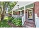 Inviting brick porch with a blue ceiling, white railing, and vibrant green plants for enhanced curb appeal at 31 Lyttleton St, Charleston, SC 29407