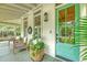 Cozy front porch with wicker chairs, a vibrant plant, and a stylish aqua-colored door at 312 Hobcaw Dr, Mount Pleasant, SC 29464