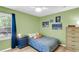Cozy bedroom with light green walls, hardwood floors, and a bright window with blue curtains at 334 Water Oak Dr, Goose Creek, SC 29445