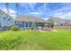 A backyard featuring a brick patio, lawn, grill, and outdoor dining set in front of the blue paneled house at 359 Whispering Breeze Ln, Summerville, SC 29486