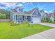 Charming two-story home with landscaped yard and cozy front porch featuring green lawn and flowering plants at 359 Whispering Breeze Ln, Summerville, SC 29486