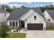 Charming single-Gathering home featuring stone accents, a dark two-car garage, and manicured landscaping at 404 Omaha Dr, Moncks Corner, SC 29461