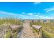 Sandy beach access with wooden walkway and views of the ocean, beach umbrellas and blue sky at 4403 Sea Forest Dr, Kiawah Island, SC 29455