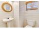 Stylish powder room featuring shiplap walls, rope mirror, and a pedestal sink at 4403 Sea Forest Dr, Kiawah Island, SC 29455