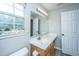 Well-lit bathroom featuring a large mirror, wood vanity, and a window with decorative succulents at 5128 Thornton Dr, Summerville, SC 29485