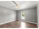 Bright bedroom with a ceiling fan and large window, showcasing the wood-look laminate flooring at 513 Pauline Dr, Bonneau, SC 29431
