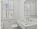 All-white bathroom with large mirror, window, and porcelain sink at 71 E Bay St, Charleston, SC 29401