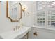 Elegant bathroom with a pedestal sink, gold fixtures, and plantation shutters at 71 E Bay St, Charleston, SC 29401