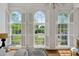 Bright bedroom featuring three large windows with white shutters and a view of the lush greenery outside at 71 E Bay St, Charleston, SC 29401