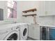 Bright laundry room with modern appliances, subway tile, floating shelves, and a beverage fridge at 71 E Bay St, Charleston, SC 29401