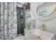 Bathroom features a round mirror, blue tiled shower and decorative print shower curtain at 7639 Hillandale Rd, North Charleston, SC 29420