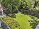 Large backyard with lush grass, tennis court, and bordered by mature trees and fencing at 8 Pony Ln, Charleston, SC 29407