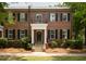 Charming brick townhome featuring a covered entryway, black shutters, and manicured landscaping at 861 Center Park St, Charleston, SC 29492
