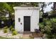 Charming white outbuilding with black door and brick walkway, surrounded by lush landscaping and decorative stone at 861 Center Park St, Charleston, SC 29492