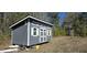 Well-built shed with white trim, featuring a door and multiple windows providing additional storage space at 934 Tiger Loop, Saint Stephen, SC 29479