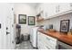 Bright laundry room featuring white cabinets, wooden countertops, washer, dryer, and stylish patterned flooring at 1015 Jacksnipe Ln, Mount Pleasant, SC 29464