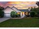 Charming single-story home with manicured landscaping, white siding and a dramatic sunset backdrop at 1077 Farmington Rd, Charleston, SC 29412